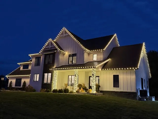 Two story home with pillars outlined in Christmas lights